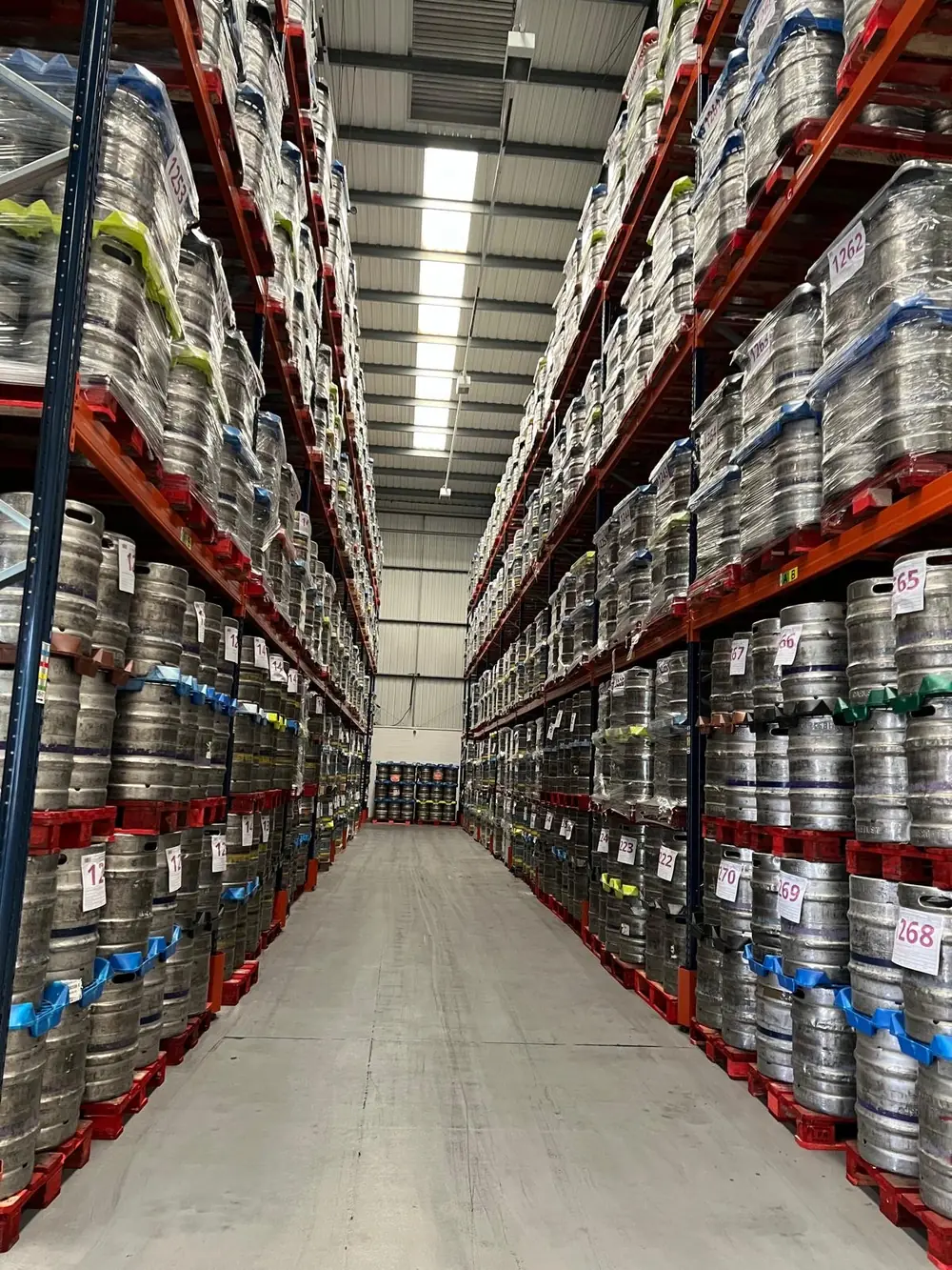 Warehouse aisle racked floor to ceiling with beer kegs