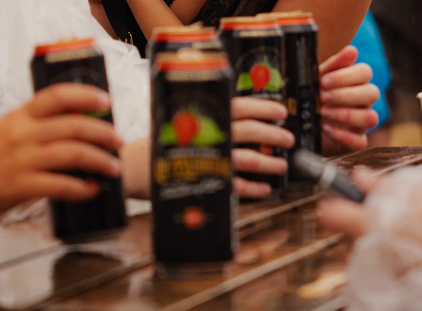 Cans of fruit cider being handed over a bar