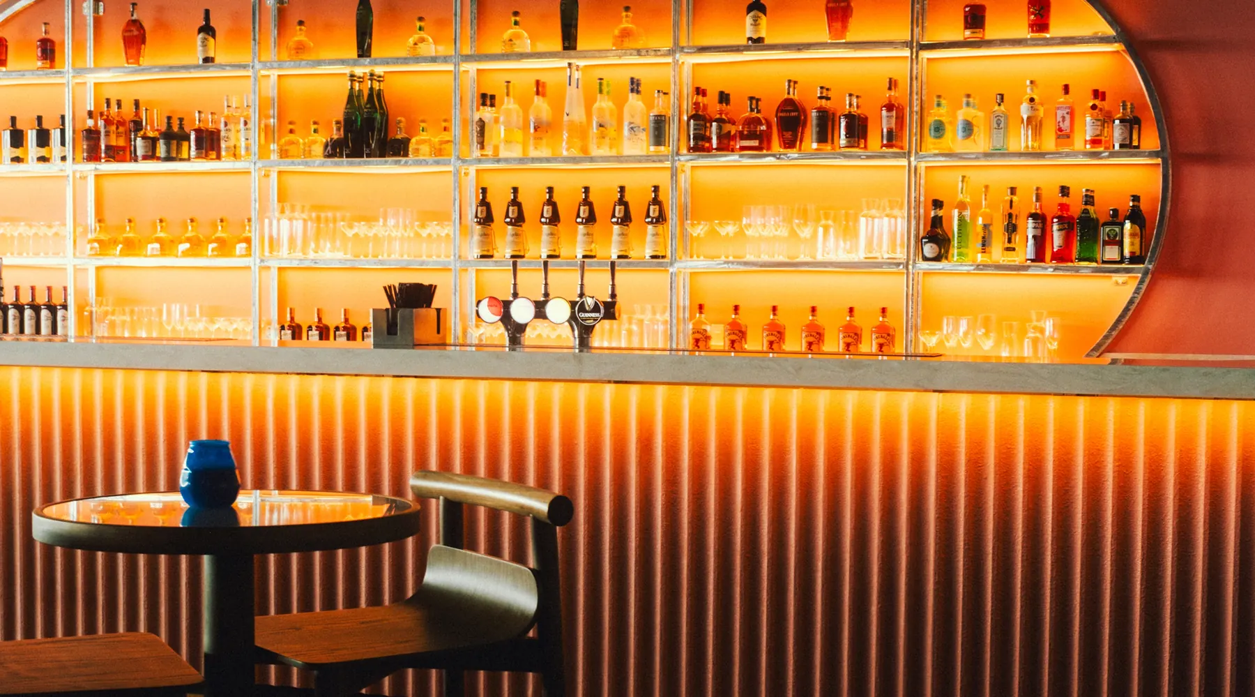 Backlit bar stocked with spirits, wine and draught taps