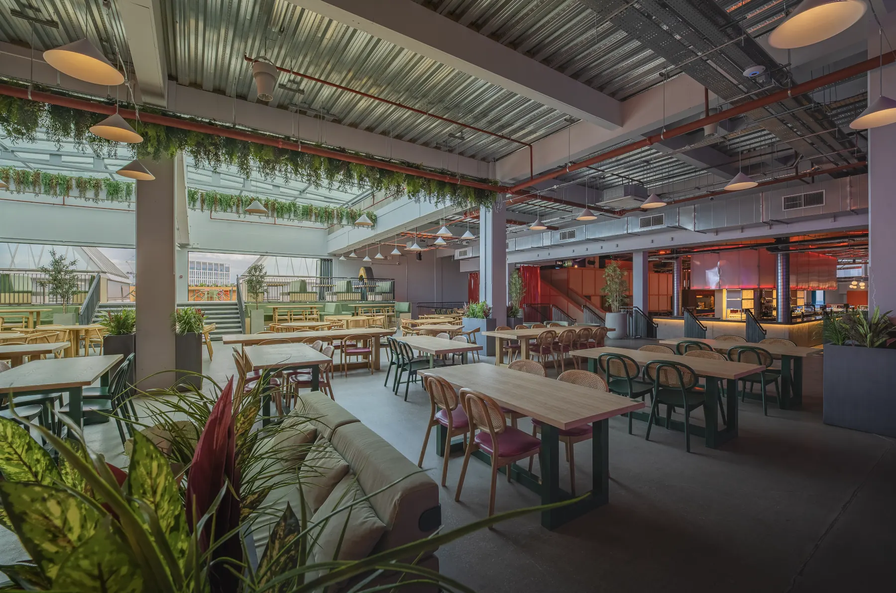 Food hall dining space with long tables, plants and a bar